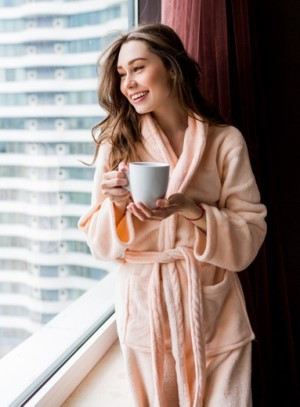 fresh-young-woman-pink-tender-bathrobe-drink-tea-looking-out-window_273443-3091